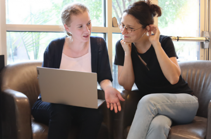 Two people discussing research over a laptop